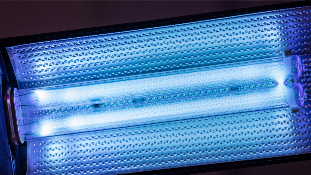 A close-up of a glowing blue UV-C germicidal light installed in an air handler, representing the professional solution for killing mold and bacteria on the A/C evaporator coil.