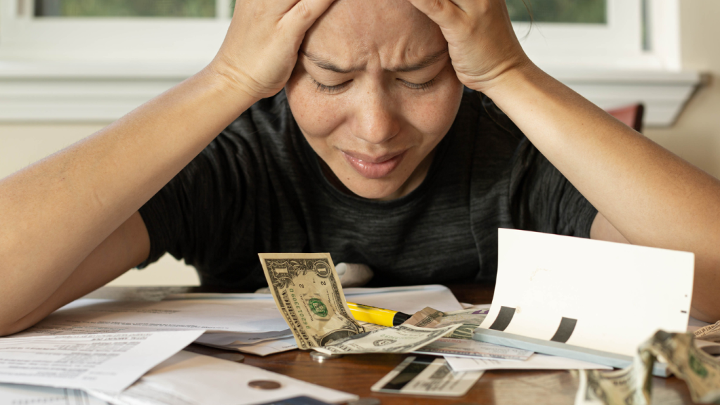 A stressed couple reviewing high bills and paperwork, illustrating the financial burden of expensive repairs and inefficiency caused by an old air conditioning system.